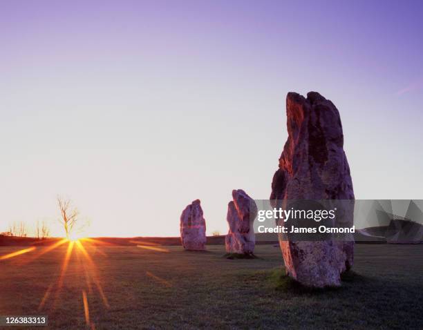 standing stones at avebury at sunrise on the vernal (spring) equinox, designated a unesco world heritage site, the purpose of the ancient obelisks remains an enigma - equinox stockfoto's en -beelden