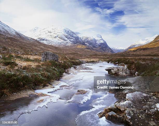 frozen river & view towards the three sisters of glencoe in scotland. the effects of glaciation, and millions of years and many cycles of erosion have subsequently carved and worn the rocks away into the formation we know today. glencoe has some of the mos - baron photos et images de collection