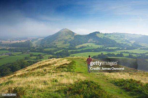 caucasian male walker (30 years old) on caer caradoc heading for the lawley, shropshire, england, uk - shropshire stock pictures, royalty-free photos & images