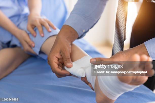 broken leg patient on the bed ,doctor or physiotherapist giving the expert treatment to the broken leg patient on the bed for a good recovery,patient with knee problem at consulting room - wunde stock-fotos und bilder