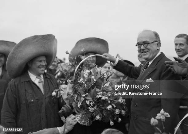 Remise d'un bouquet de muguet par les forts des Halles à l'arrivée du président de la République Vincent Auriol à l'aéroport d'Orly, après sa visite...