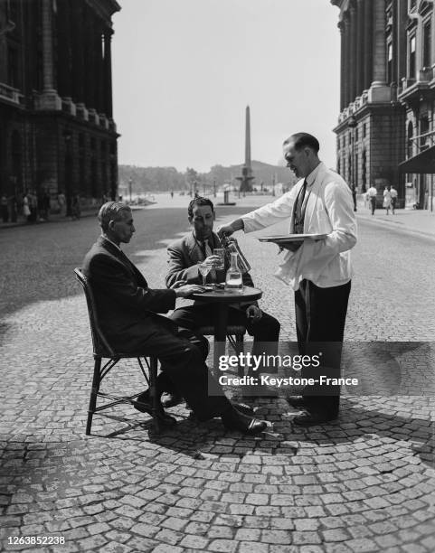 Les Parisiens ont déserté la capitale en ce 15 août 1947, on peut ainsi se faire servir l'apéritif en plein milieu de la rue Royale à Paris, France.