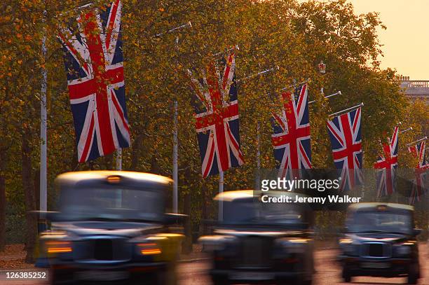 a blurred view of black london taxi cabs driving along the mall at dusk. - buckingham palace stock pictures, royalty-free photos & images