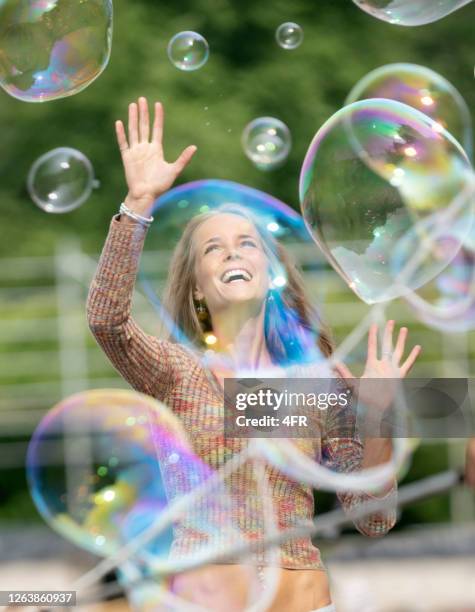 woman catching soap bubbles, playful candid lifestyle expression - bubble burst stock pictures, royalty-free photos & images