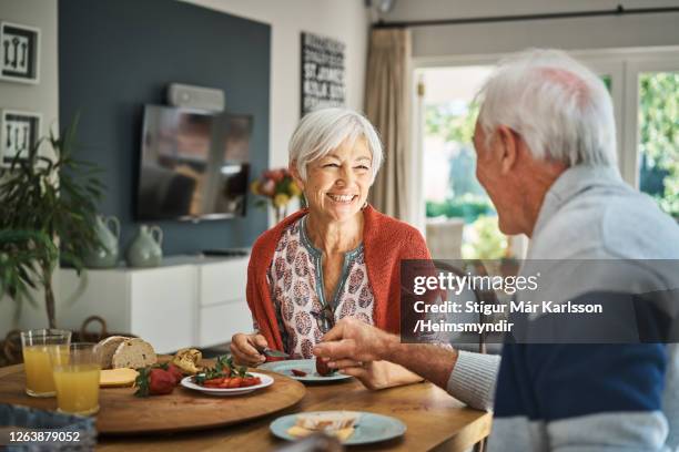 donna anziana sorridente che parla con suo marito durante la colazione - mangiare foto e immagini stock