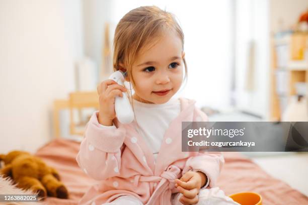 mother measuring temperature of her girl with infrared thermometer at home - thermometer turkey stock pictures, royalty-free photos & images