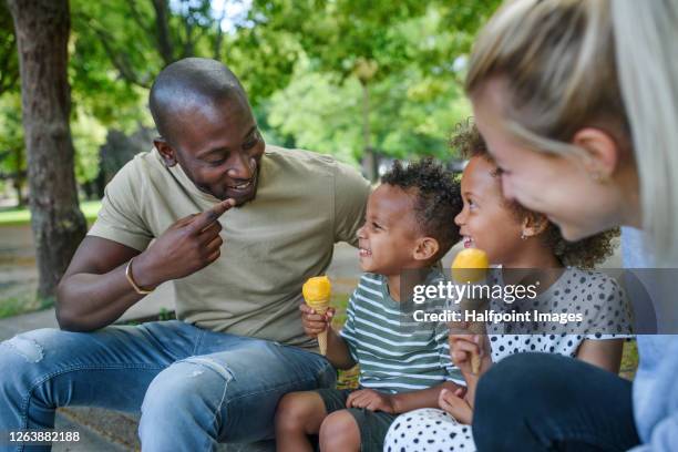 portrait of family with two small children in park in city, eating ice cream. - ice cream family stock pictures, royalty-free photos & images