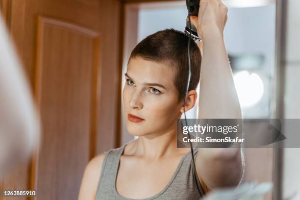 mirror reflection of young woman using hair clipper - shaved head stock pictures, royalty-free photos & images