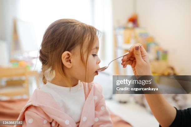 mutter gibt medizin zu kleinen mädchen - hustenmittel stock-fotos und bilder