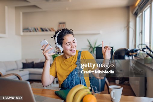 Opgewekte jonge vrouw die en aan de muziek na het werk danst Opgewekte jonge vrouw die en aan de muziek na het werk danst