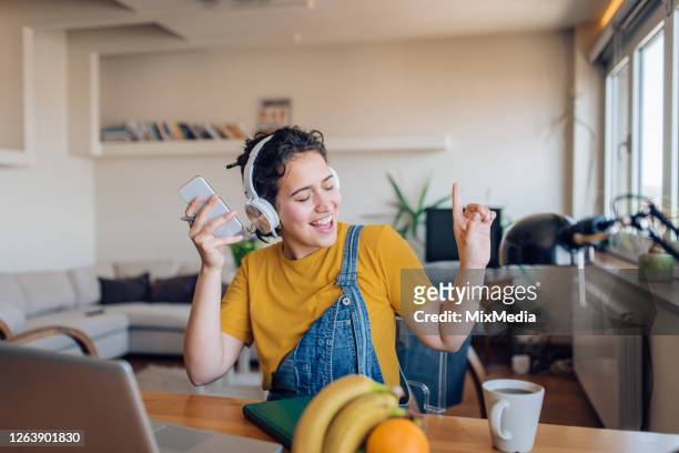 excited young woman dancing and listening to the music after work - music stock pictures, royalty-free photos & images