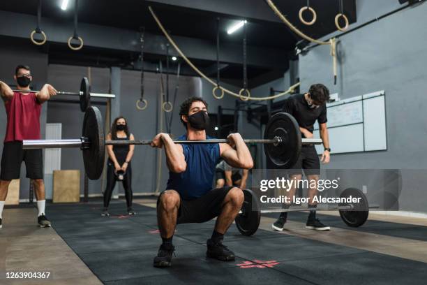 athletes lifting weight wearing protective mask - gym reopening stock pictures, royalty-free photos & images