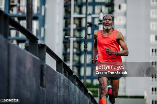 l'uomo afro-americano senior che corre in una città - longevità foto e immagini stock