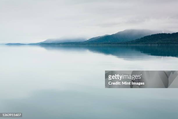 overcast sky above calm waters of an inlet in a national park. - seascape stock pictures, royalty-free photos & images