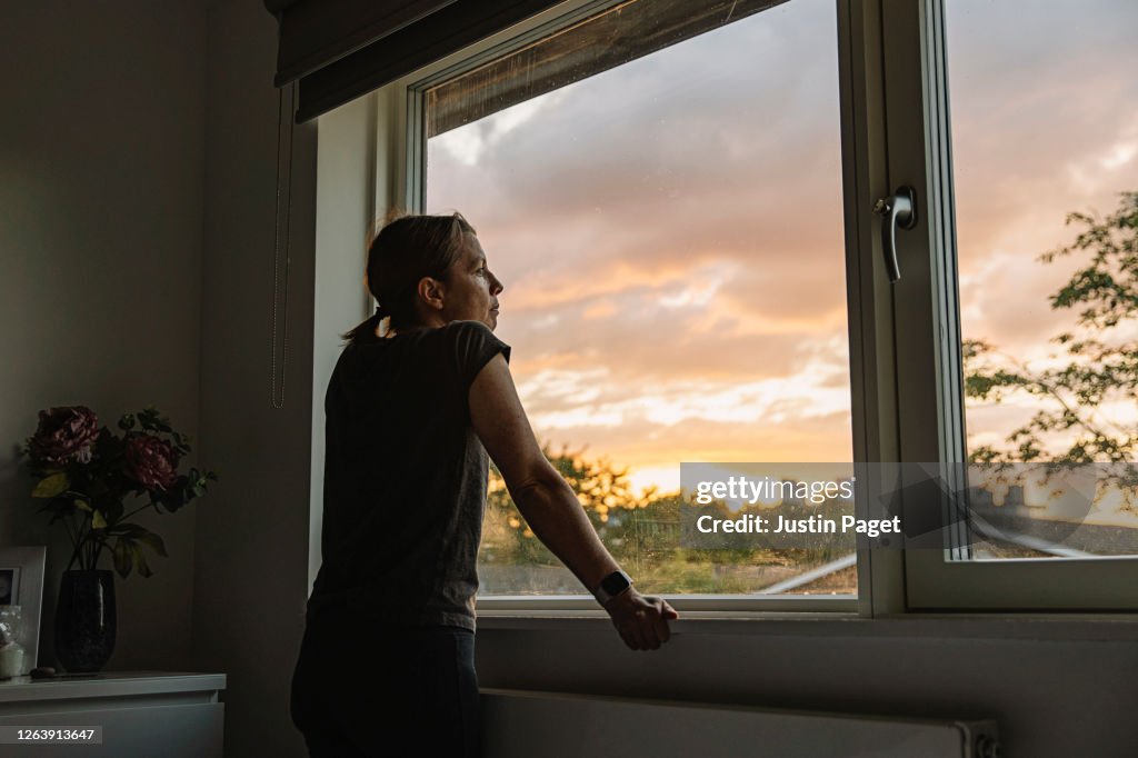 Woman looking out of window at sunset