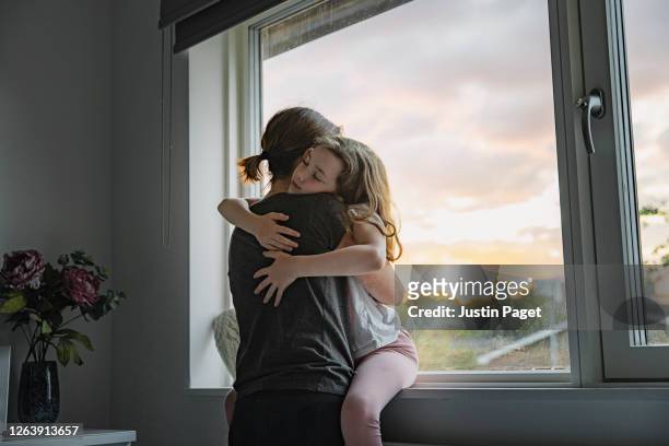 young girl getting a big cuddle from her mother - think big stockfoto's en -beelden