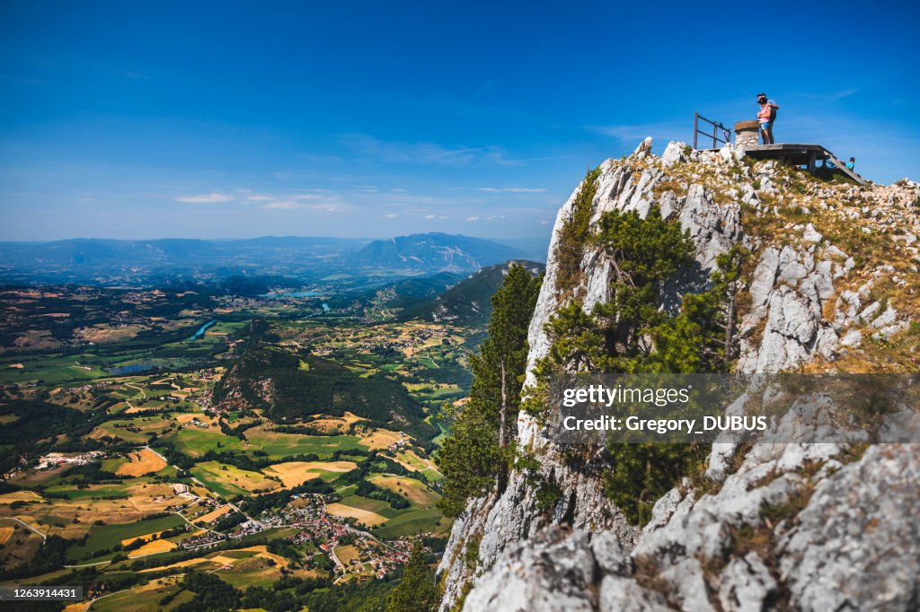 Couple of adult tourists admire the view from the mountain top over the French Alps landscape