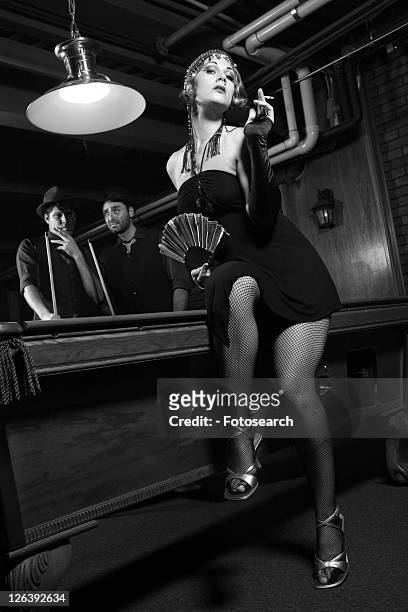 caucasian prime adult female standing in front of pool table with two caucasian prime adult men in background. - 1920s flapper girl stock pictures, royalty-free photos & images