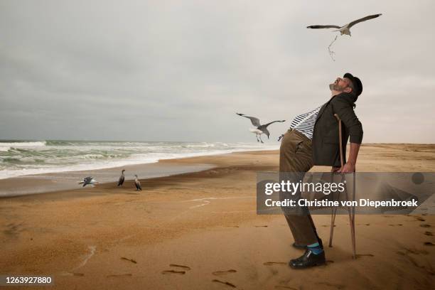 elderly man with open mouth seagull beach - bad luck foto e immagini stock