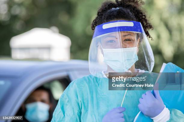 krankenschwester trägt psa lächelt bei fahrt durch testgelände - gesichtsschirm stock-fotos und bilder