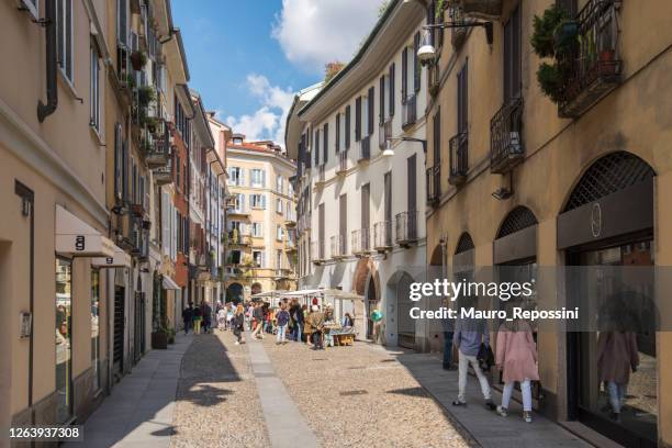 people walking next to retails kiosks in a pedestrian street in brera district at milan city, italy. - brera milan stock pictures, royalty-free photos & images