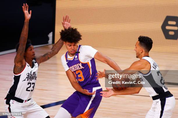 Cameron Johnson of the Phoenix Suns struggles to gain control of the ball between Lou Williams of the LA Clippers and Landry Shamet at The Arena at...