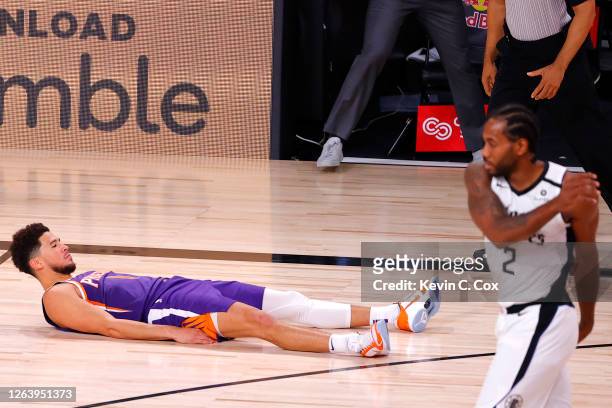 Devin Booker of the Phoenix Suns falls to the ground after scoring the game winning basket against the LA Clippers at The Arena at ESPN Wide World Of...