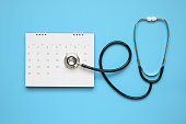 Stethoscope with calendar page date on blue background doctor appointment medical concept