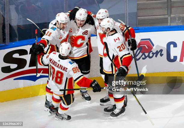 Matthew Tkachuk of the Calgary Flames is congratulated by teammates Andrew Mangiapane,Mikael Backlund,Oliver Kylington and Derek Forbort after...