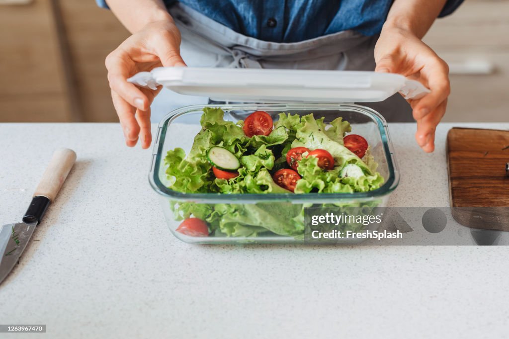 Hands of a Woman Packing a Healthy Salad into a Glass Container to be Taken Away