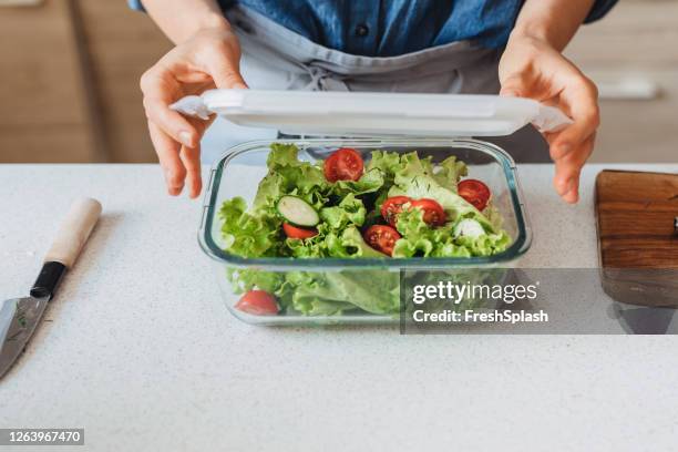 hands of a woman packing a healthy salad into a glass container to be taken away - food close up stock pictures, royalty-free photos & images