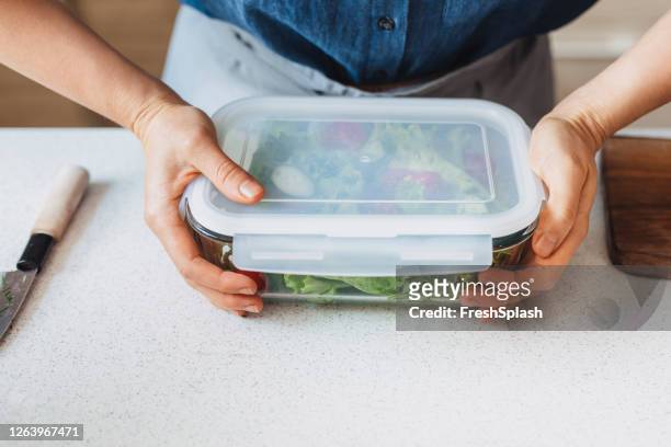 hands of a woman packing a healthy salad into a glass container to be taken away - food close up stock pictures, royalty-free photos & images