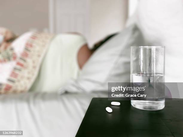 ailing woman rests in bed - schmerzmittel stock-fotos und bilder