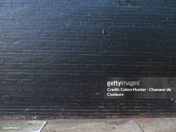 montreal old brick wall painted in black and dirty concrete sidewalk - brick wall stock pictures, royalty-free photos & images