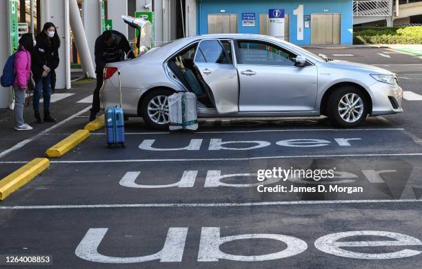 Two women load their luggage into an Uber car at Sydney Airport after arriving on Jetstar flight 510 from Melbourne on August 05, 2020 in Sydney,...