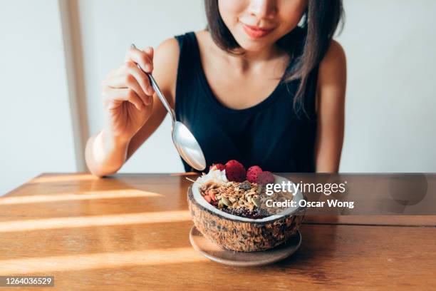 cropped shot of woman eating superfood smoothie bowl - rohkosternährung stock-fotos und bilder