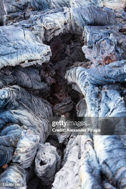 close-up view of basaltic undulating surface of frozen volcanic lava, wrinkled in folds and rolls resembling twisted rope. lava plain landscape on area eruption active volcano - rope lava stock pictures, royalty-free photos & images