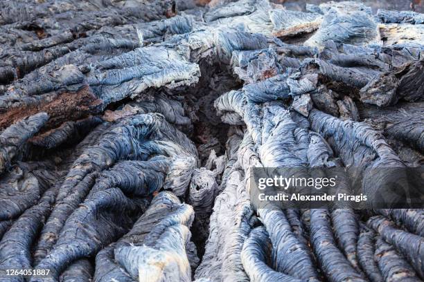 close-up view of basaltic surface of frozen volcanic lava, wrinkled in rolls and folds resembling twisted rope. lava flow landscape on eruption active volcano - rope lava stock pictures, royalty-free photos & images