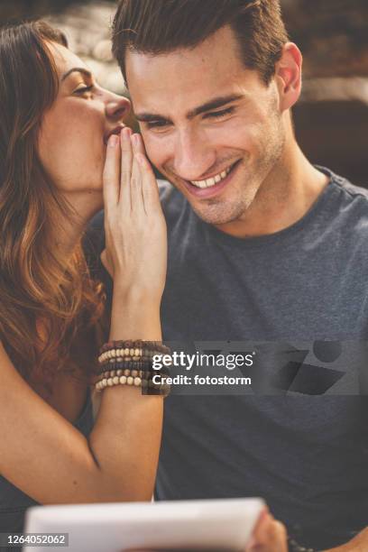 young woman whispering on his ear - woman whisper to man stock pictures, royalty-free photos & images