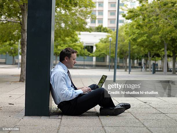 side profile of businessman sitting at roadside and using laptop - profile laptop sitting stock pictures, royalty-free photos & images