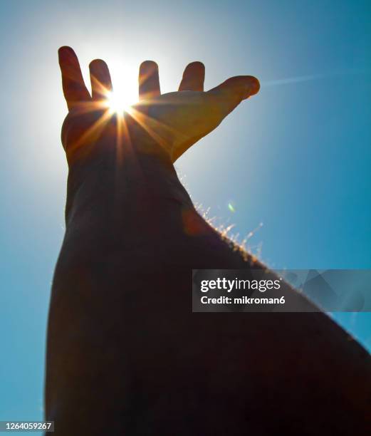 outstretched hand towards the sun wanting to touch it - stretching fingers stock-fotos und bilder