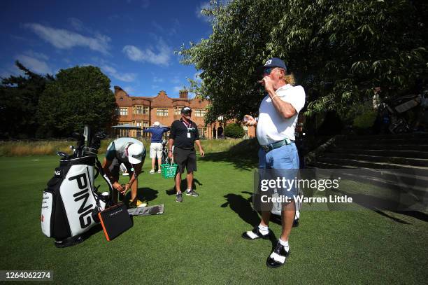 Miguel Angel Jimenez of Spain lights a cigar in front of Hanbury Manor watched by caddie Kyle Roadley ahead of the English Championship at Hanbury...