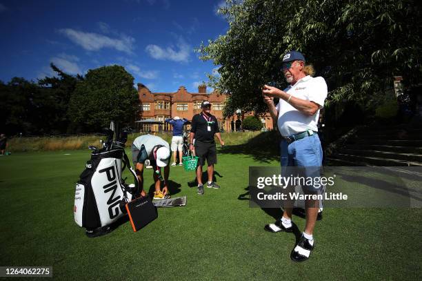 Miguel Angel Jimenez of Spain lights a cigar in front of Hanbury Manor watched by caddie Kyle Roadley ahead of the English Championship at Hanbury...