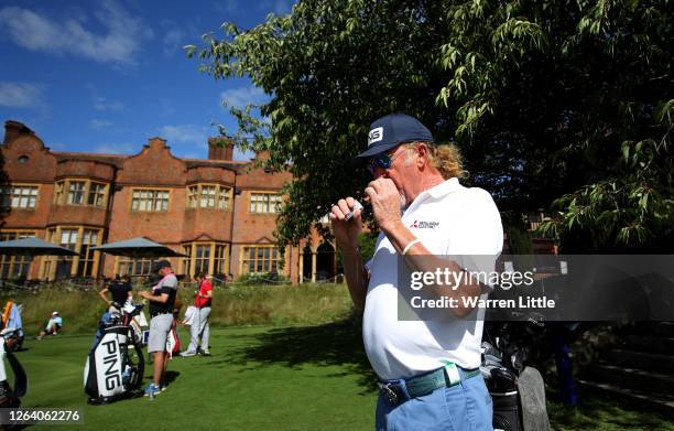 Miguel Angel Jimenez of Spain lights a cigar in front of Hanbury Manor watched by caddie Kyle Roadley ahead of the English Championship at Hanbury...