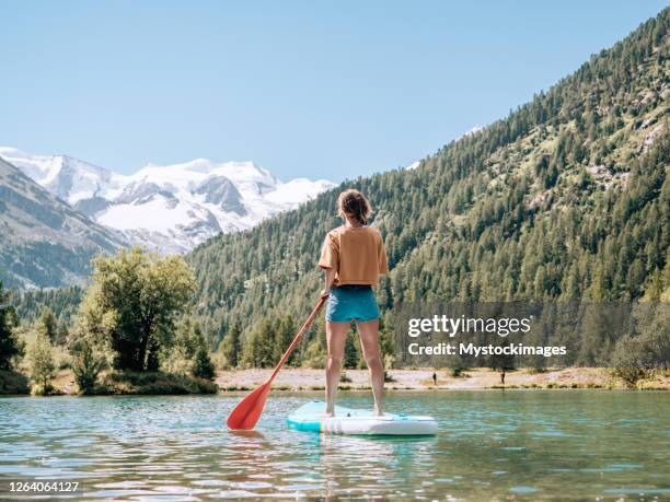stand up paddle mit aussicht, frau auf sup in den bergen mit blick auf den gletscher - frau ruhige szene berge stock-fotos und bilder
