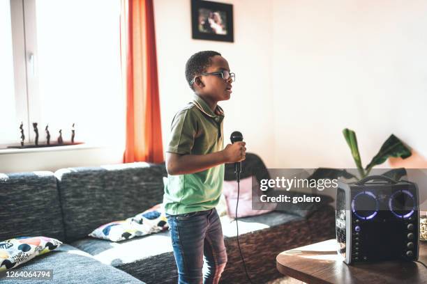 kleiner junge singt mit karaoke-maschine im wohnzimmer - boy singing stock-fotos und bilder