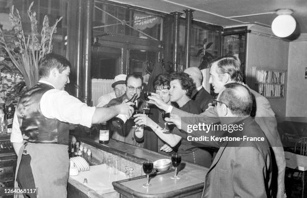 Des clients portent un toast au comptoir d'un bistrot parisien en novembre 1969, Paris, France.