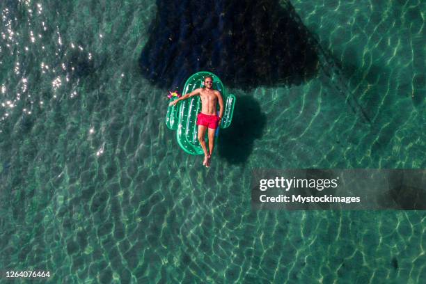 aerial view of man floating on lake with inflatable cactus sunbathing - pool raft stock pictures, royalty-free photos & images