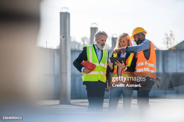 construction site development team checking digital tablet - reflective clothing stock pictures, royalty-free photos & images