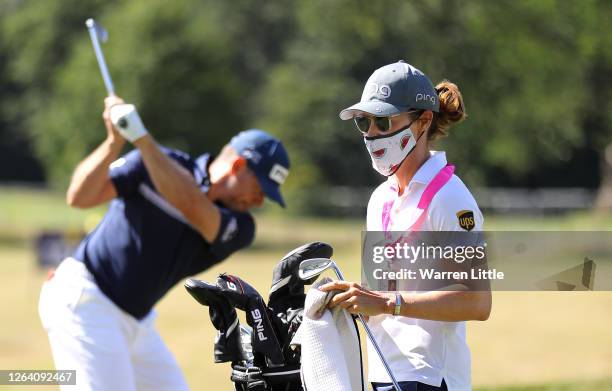 Lee Westwood of England practices on the range as fiancée and caddie, Helen Storey cleans his clubs ahead of the English Championship at Hanbury...